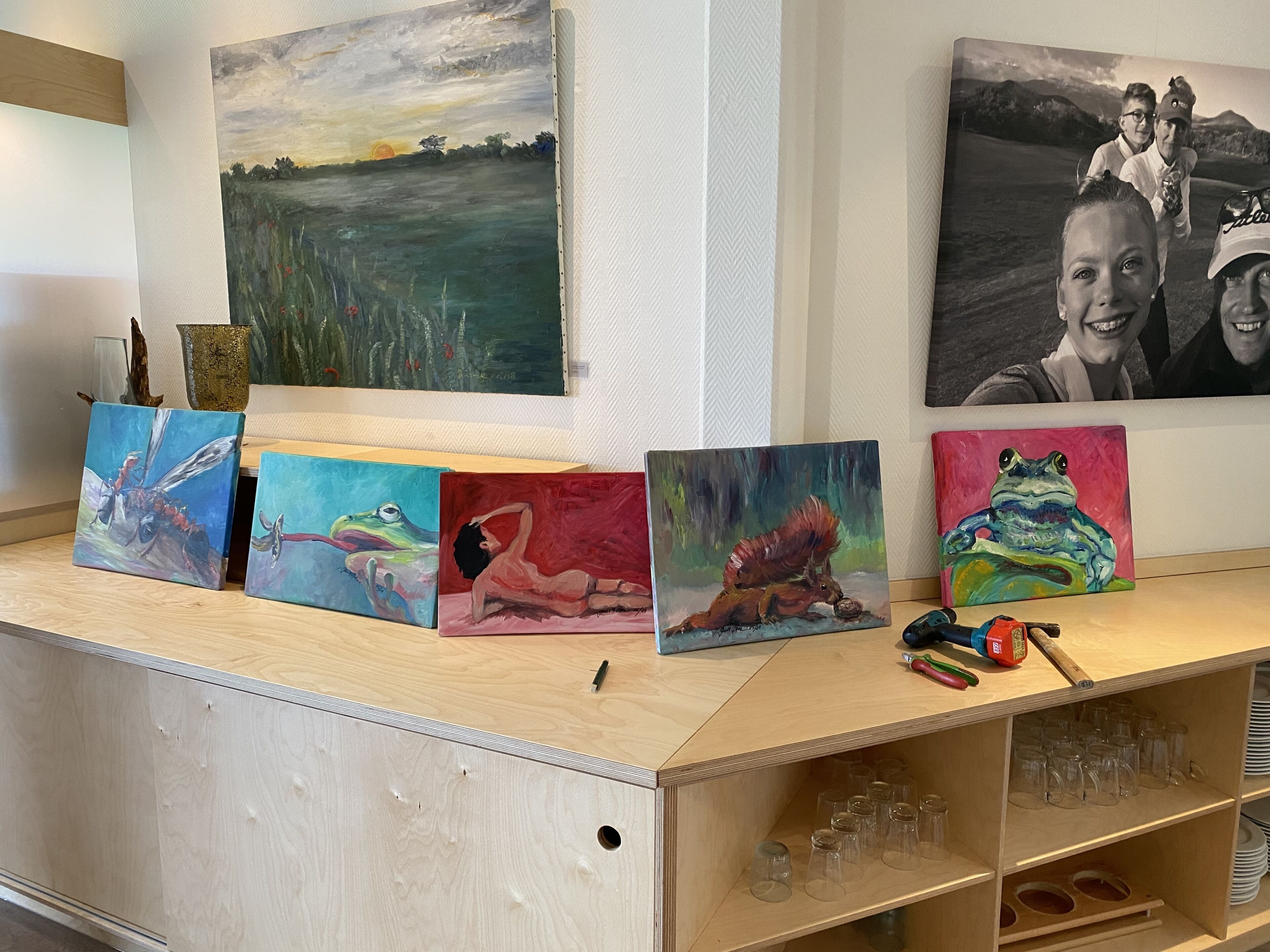 A wooden counter with various paintings and a few items on it.
