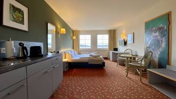 Ein Hotelzimmer mit Bett, Schreibtisch, Stuhl und einer Küchenzeile.