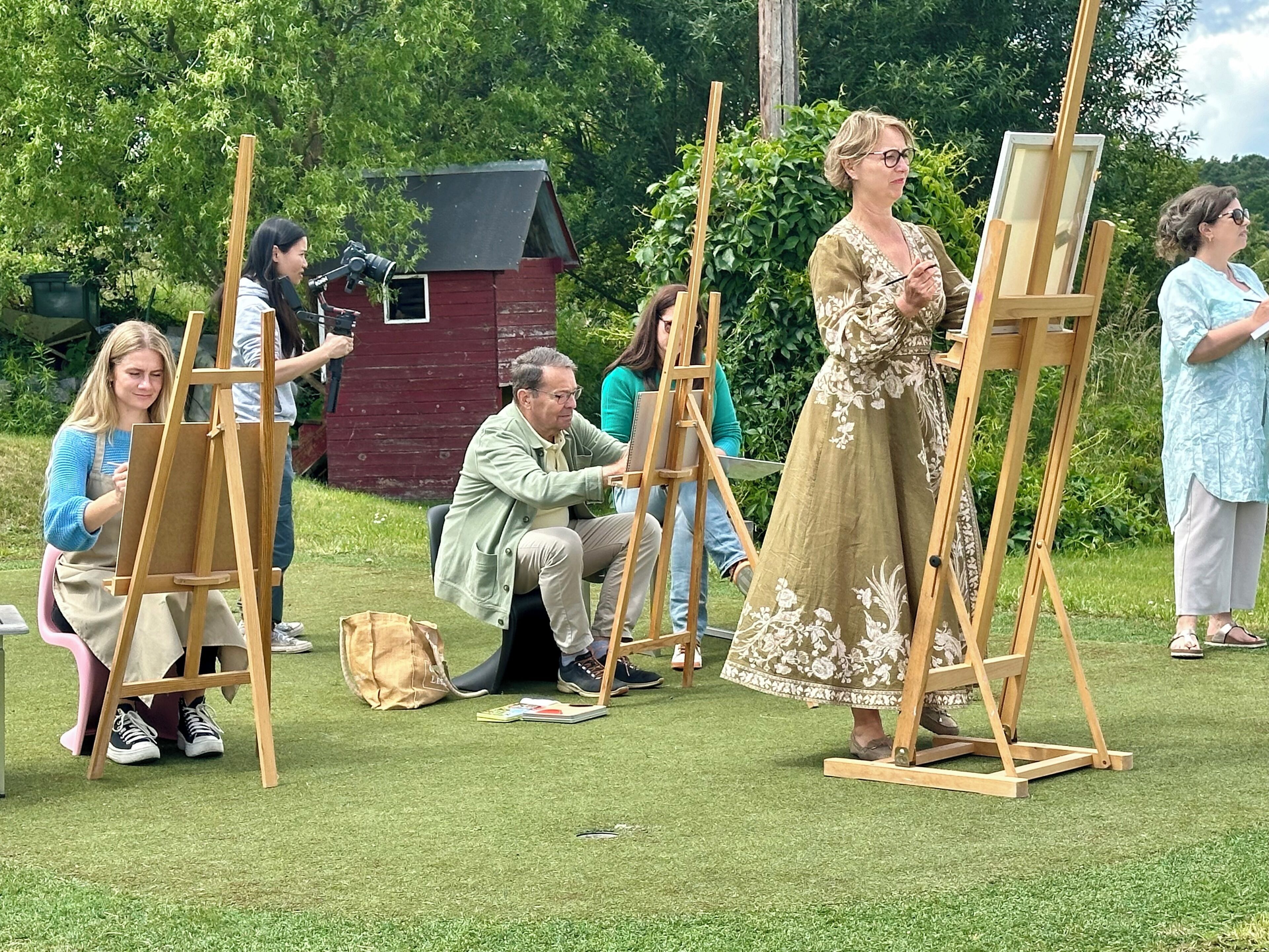 Un grupo de personas pintando al aire libre sobre caballetes.