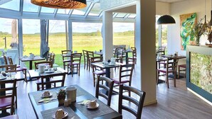 A restaurant with outdoor seating, large windows, and a view of the countryside. - Hotel am Müritz-Nationalpark (Waren (Müritz))