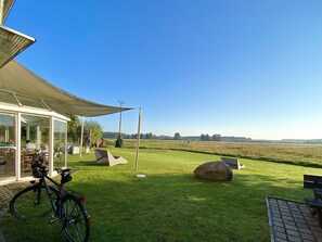 Een overdekt terras met uitzicht op een grasveld.