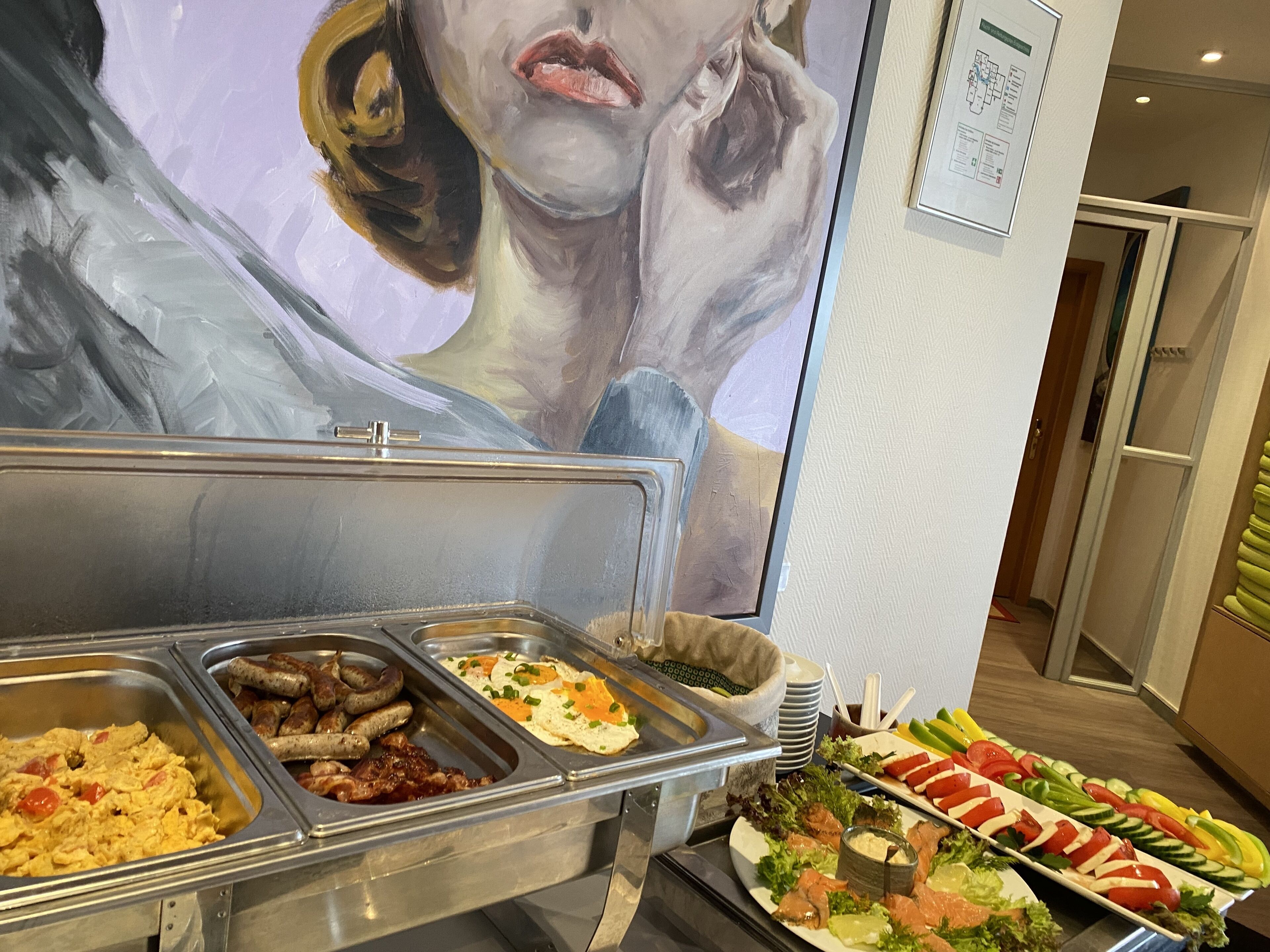 A buffet with various food options including eggs, sausages, and salads.
