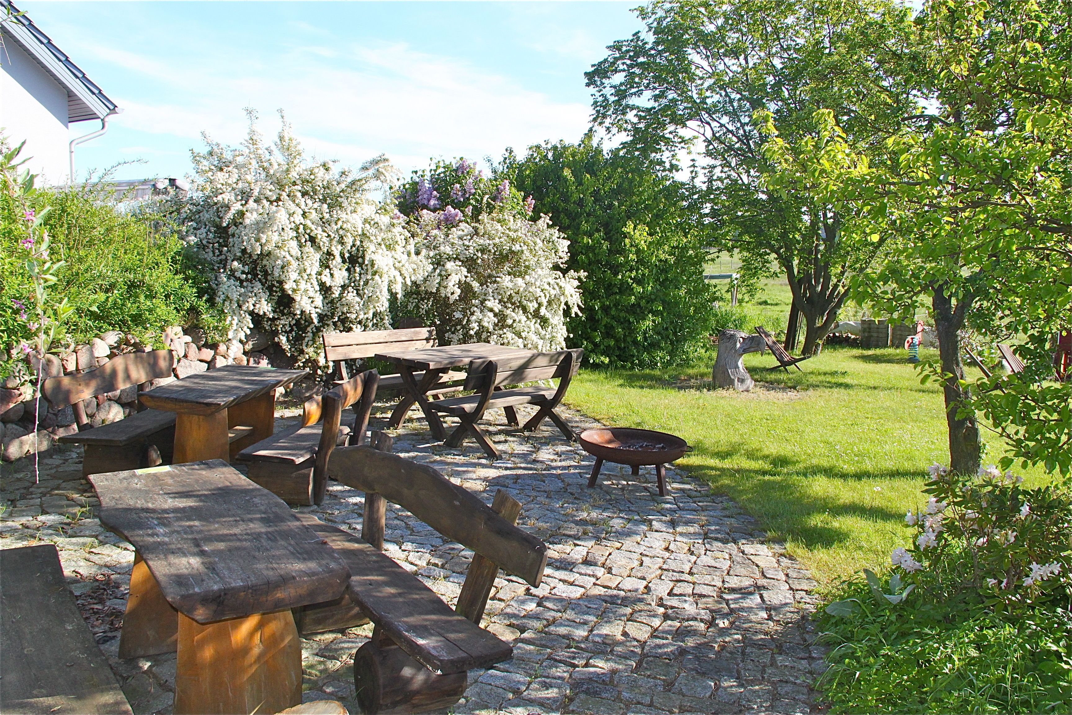 Un patio al aire libre con suelo de piedra, bancos de madera y una chimenea.