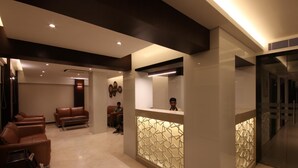 Un área de recepción moderna con un mostrador, zona de estar y un refrigerador grande.
