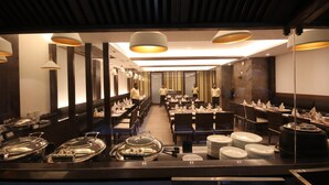 Un restaurante con mesas largas comunitarias, iluminación colgante y un diseño de interiores moderno.