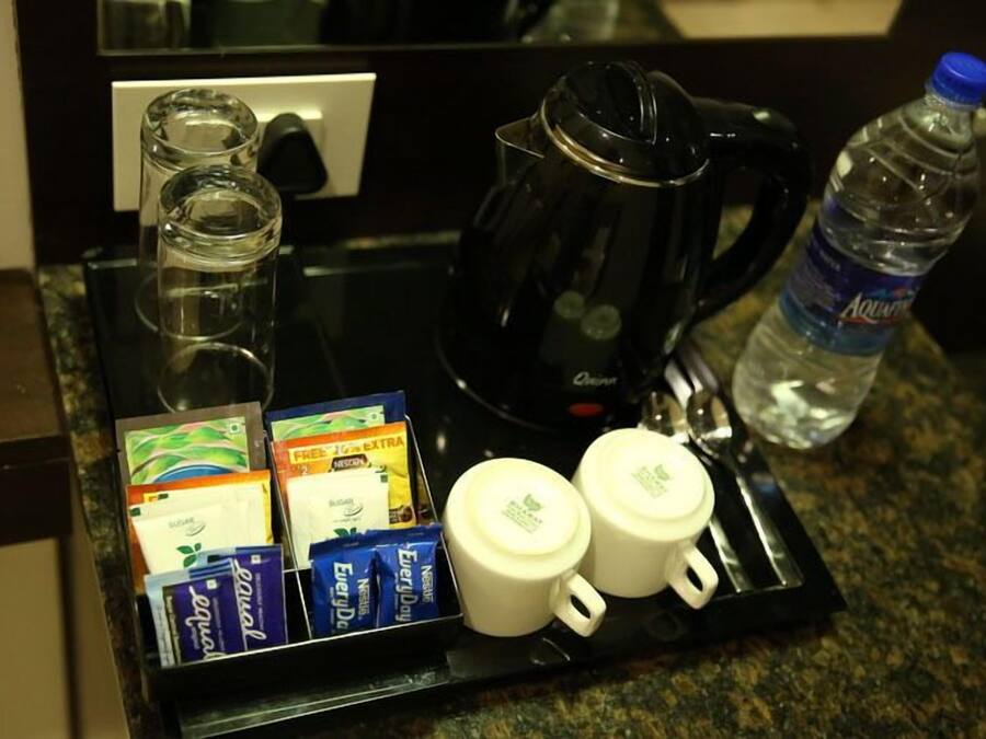 A breakfast tray with coffee maker, water bottle, sugar packets, and coffee cups.