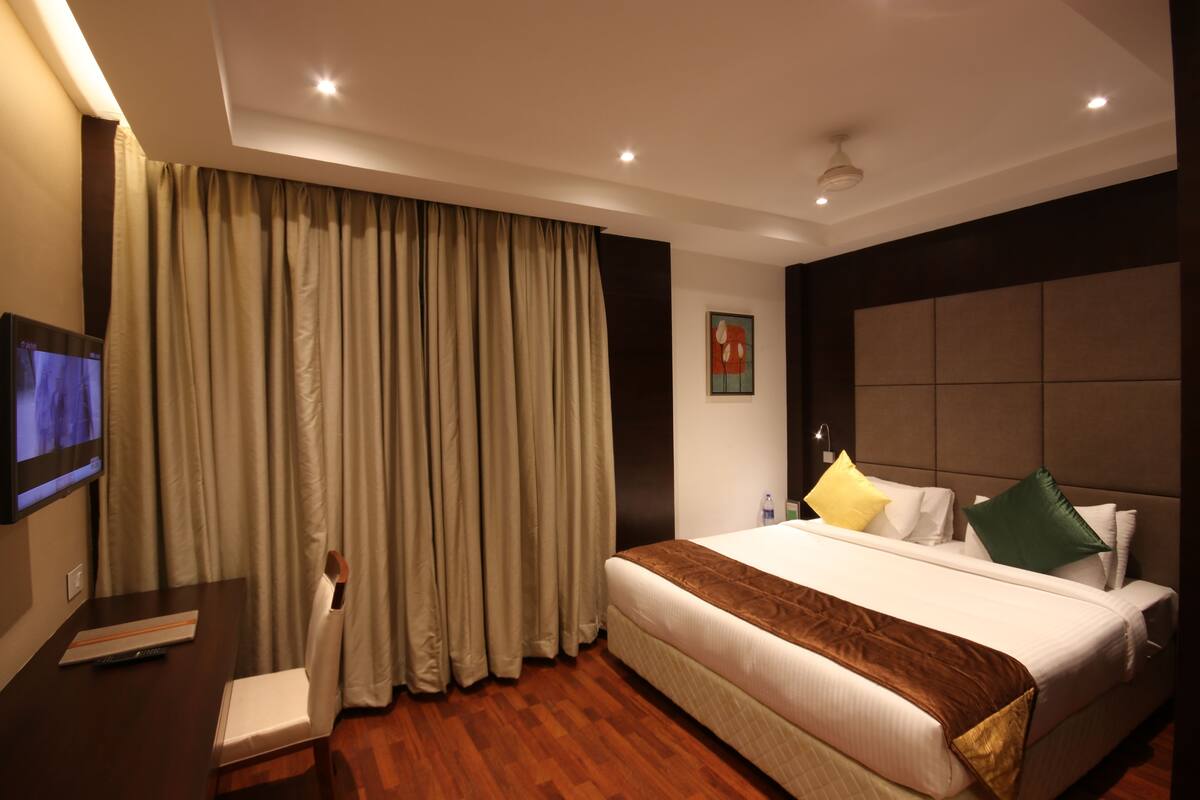 A hotel room with a large bed, a flat-screen TV, a desk, and a chair.
