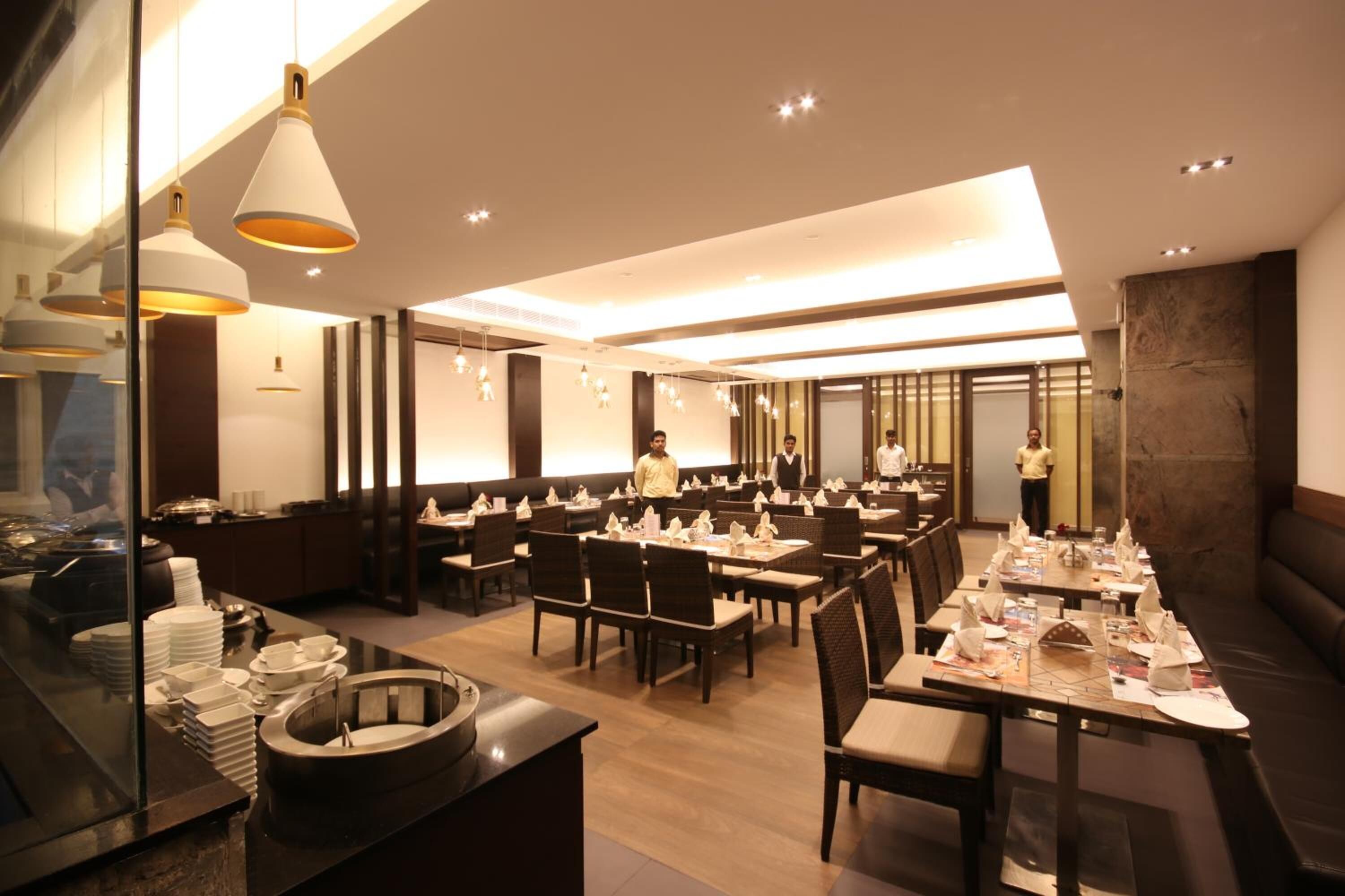 Un restaurante moderno con varias mesas, una zona de buffet y un bar.