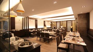 Un restaurante moderno con varias mesas, una zona de buffet y un bar.