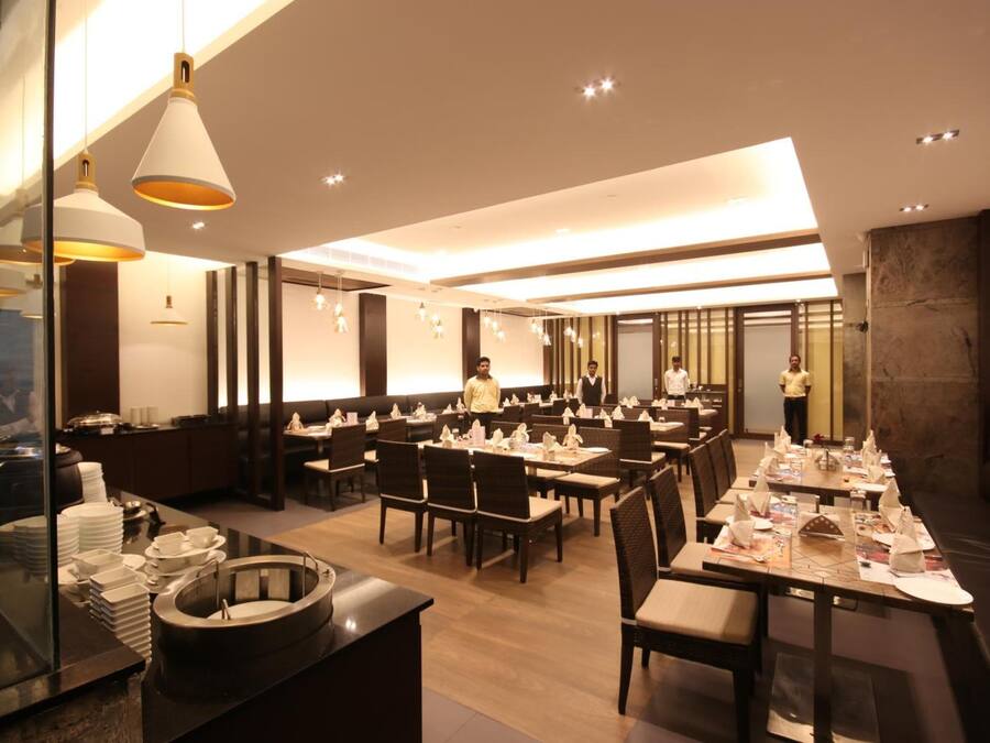 Un restaurante moderno con varias mesas, una zona de buffet y un bar.