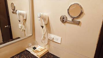 A bathroom with two hair dryers mounted on the wall, a small mirror, and a vanity area with a countertop.