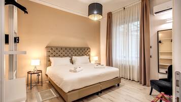 A well-lit bedroom with a large bed, bedside lamps, a hanging light fixture, and a wardrobe.