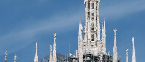 A Gothic-style cathedral with intricate spires and a golden statue on top, under construction with scaffolding.