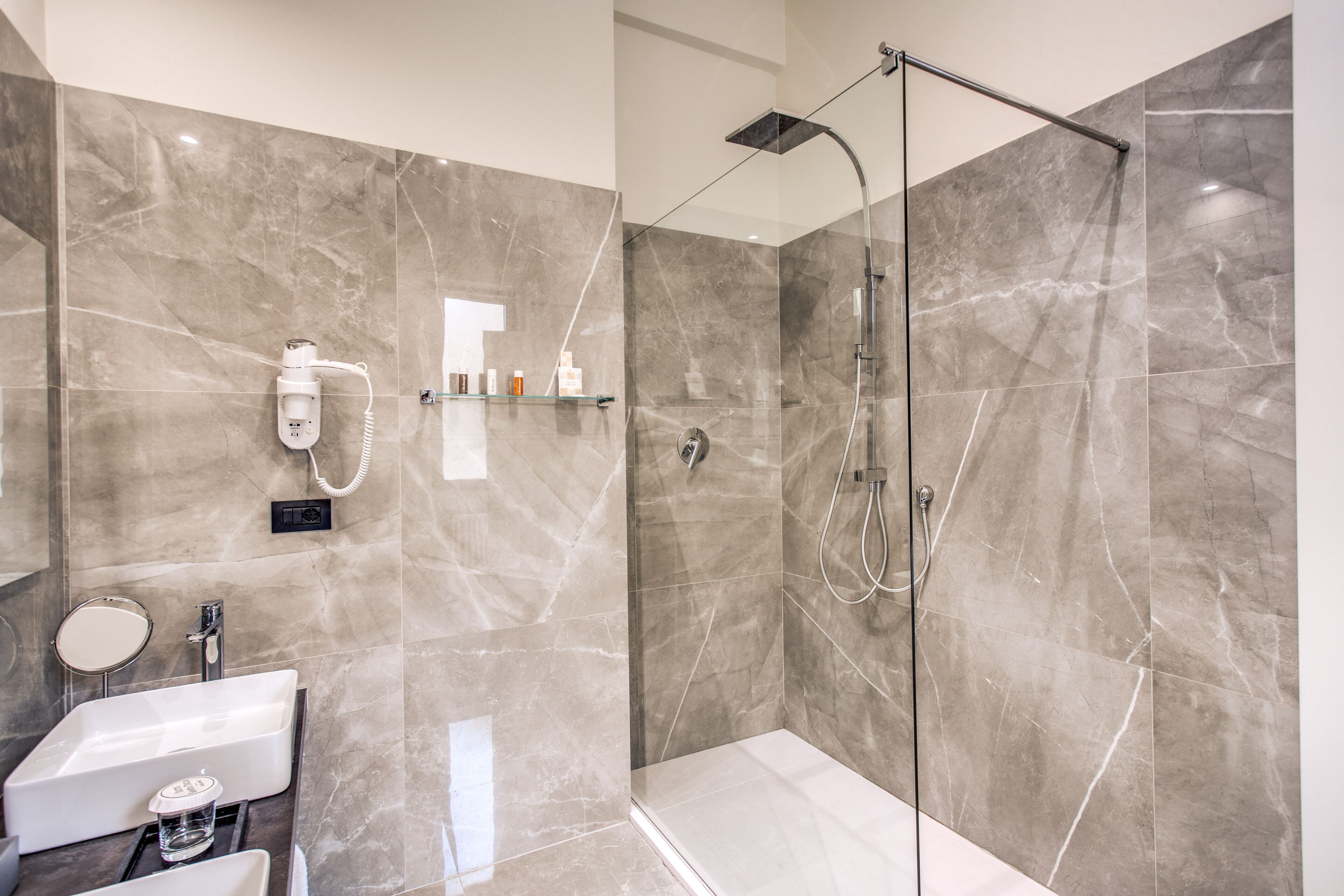 A modern bathroom with a glass-enclosed shower, a built-in sink, and a vanity with a mirror.