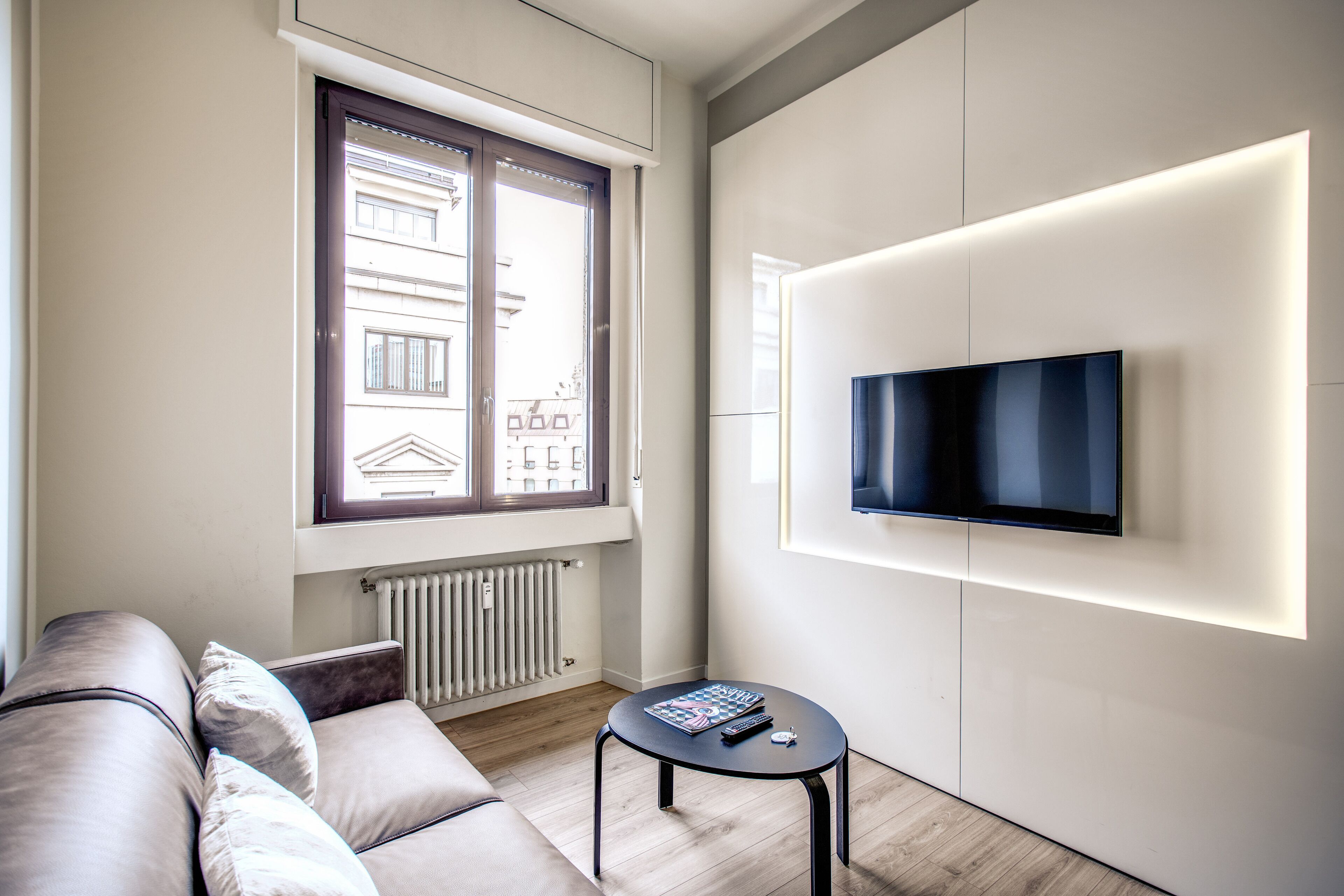 A modern living room with a sofa, a small table, and a mounted TV.