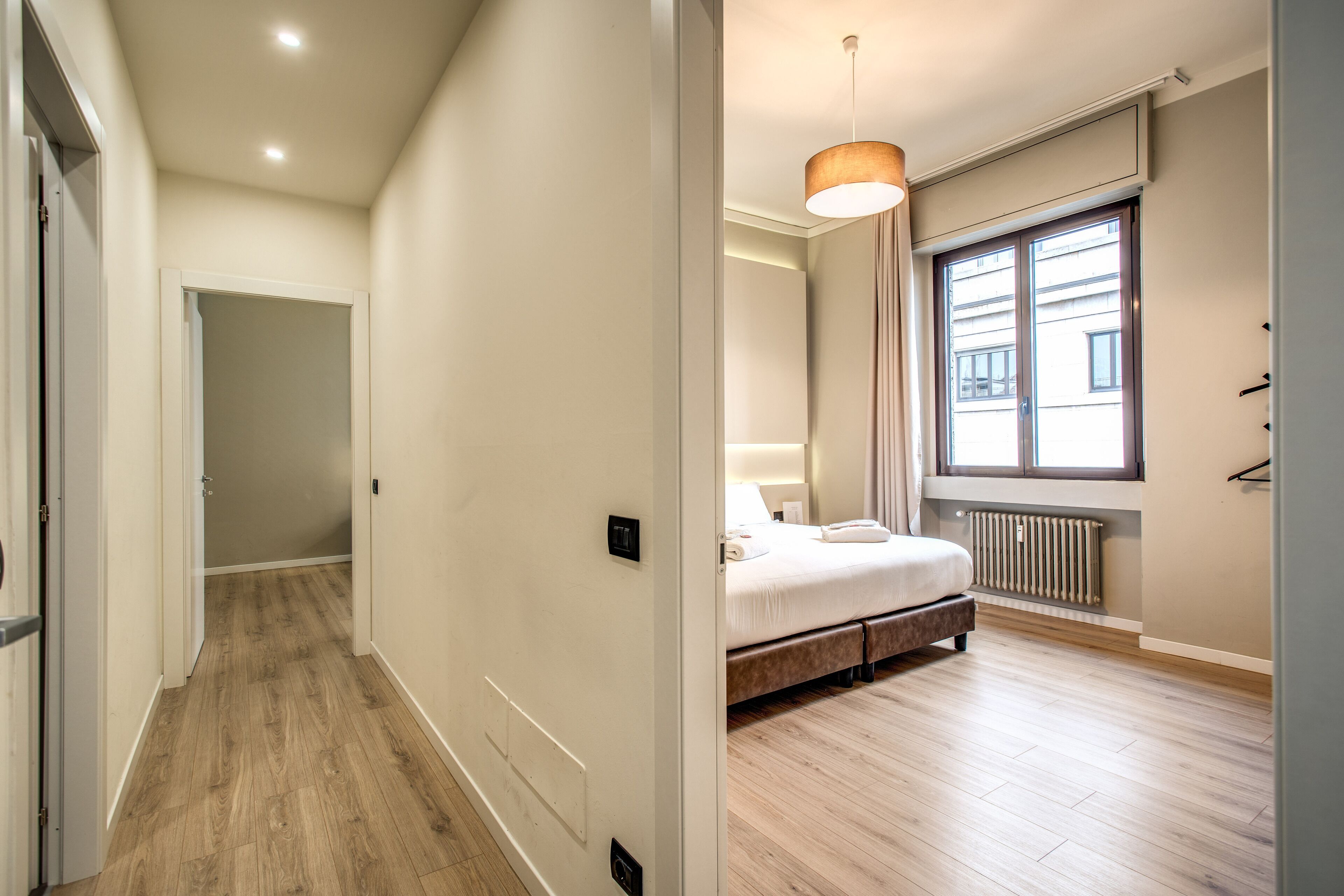 Een slaapkamer met een bed, een raam en een radiator.