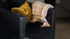 A cozy living room with a dark sofa, two candles on a mantel, and a fireplace. - Blåtind Boutique Hotel (Stordal)