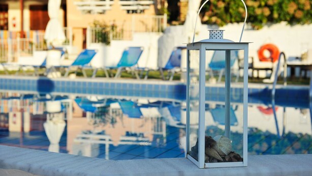 Ein Poolbereich mit Liegestühlen und einer Laterne.
