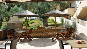 Eine Terrasse im Freien mit zwei Reetdach-Sonnenschirmen, Backsteinmauern und Gartenmöbeln.