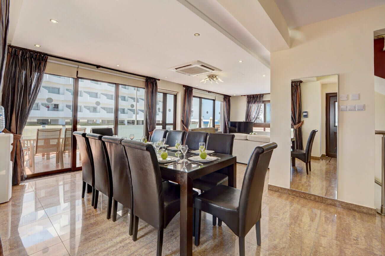 Un espace repas moderne avec une grande table, des chaises noires et une vue sur le bâtiment extérieur.