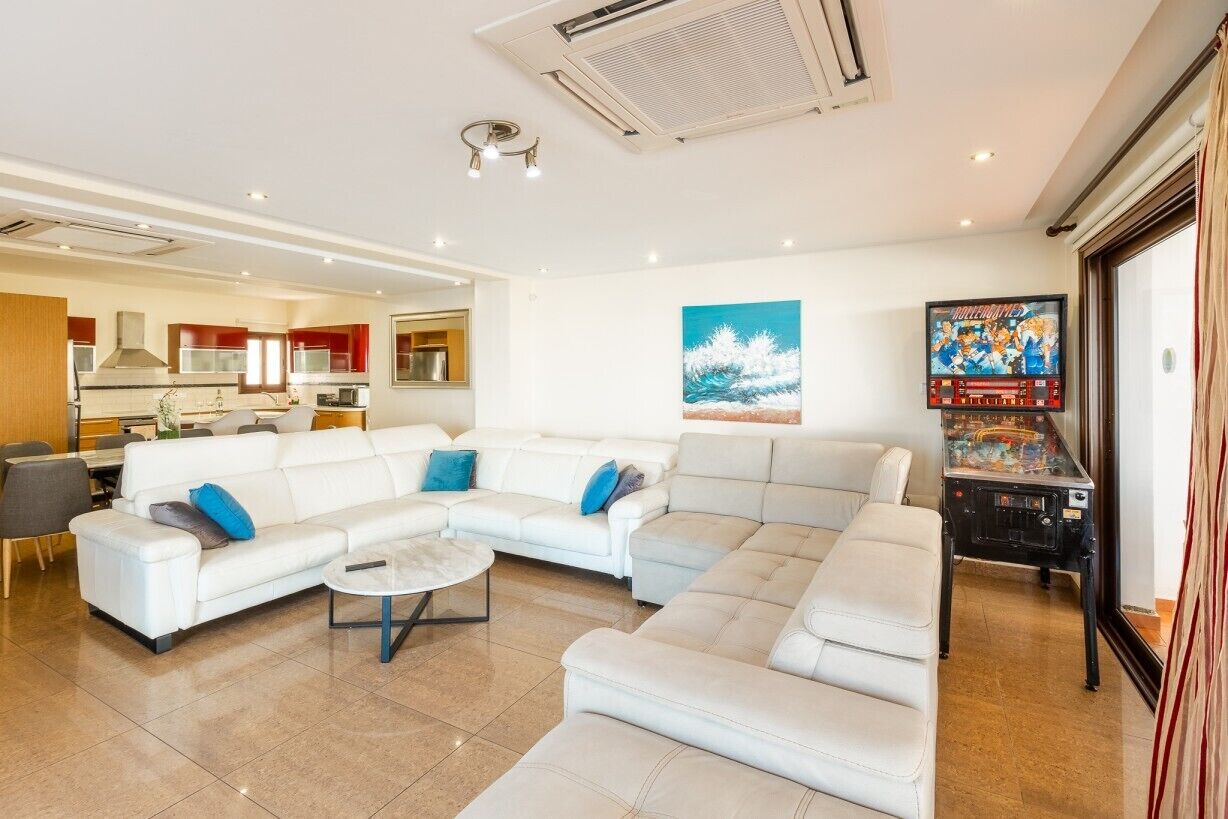 A modern living room with a sectional sofa, a coffee table, and a game console.