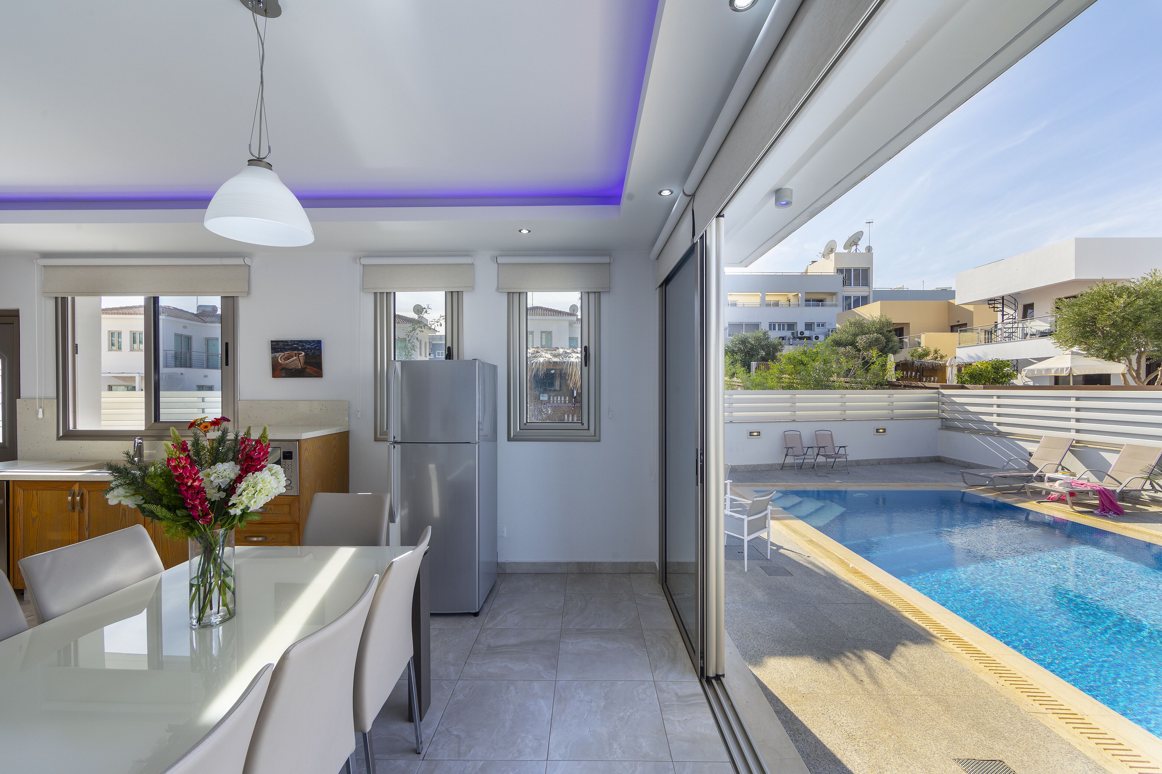 Una cocina moderna con comedor, refrigerador y vistas a una piscina.