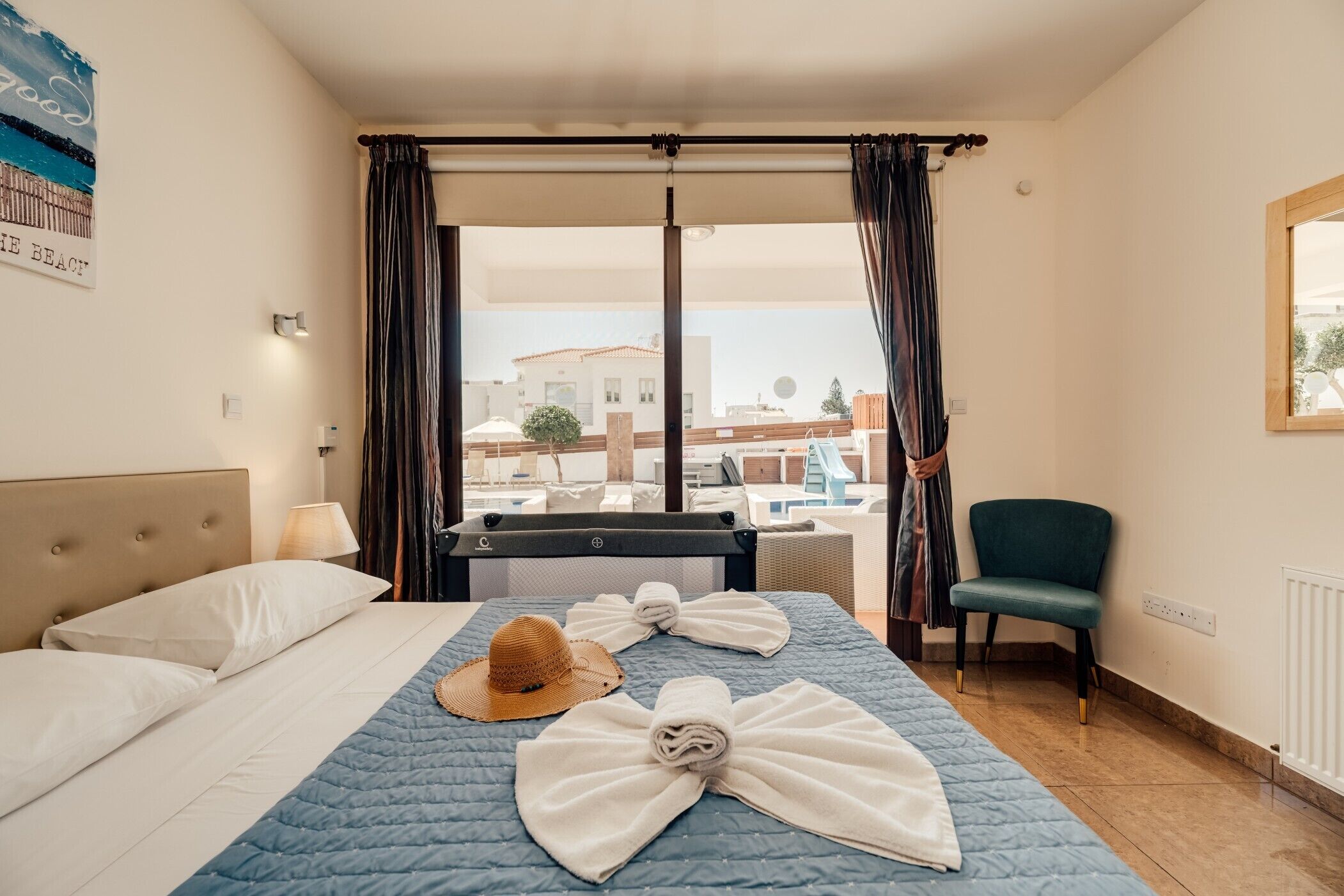 A hotel room with a bed, a chair, a view of the beach, and a window with curtains.