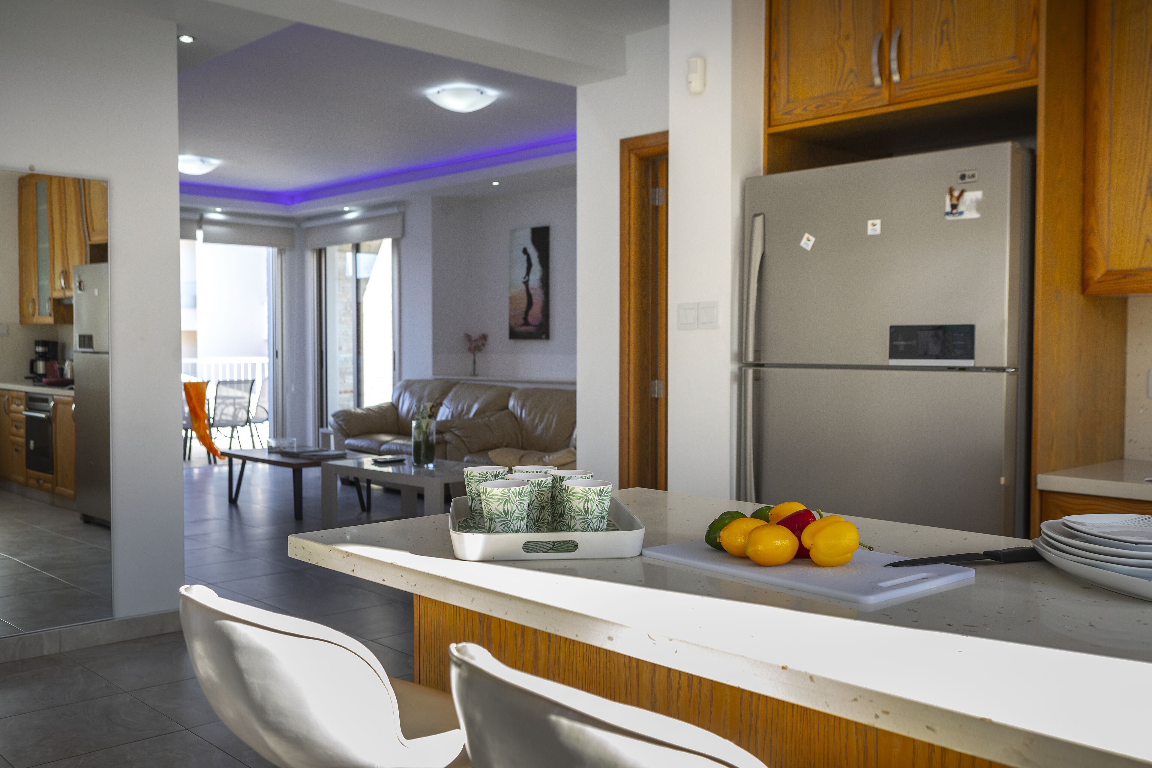 A modern kitchen with a refrigerator, a dining area with a table and chairs, and a living room with a sofa and a coffee table.