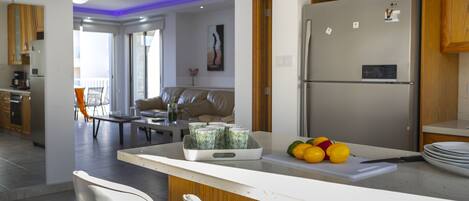 A modern kitchen with a refrigerator, a dining area with a table and chairs, and a living room with a sofa and a coffee table.