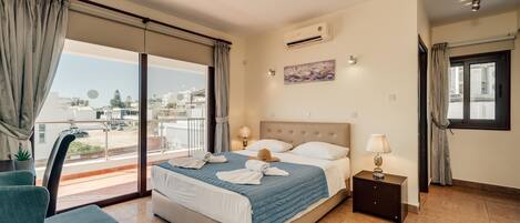 A hotel room with a bed, a chair, a nightstand, and a window with curtains.
