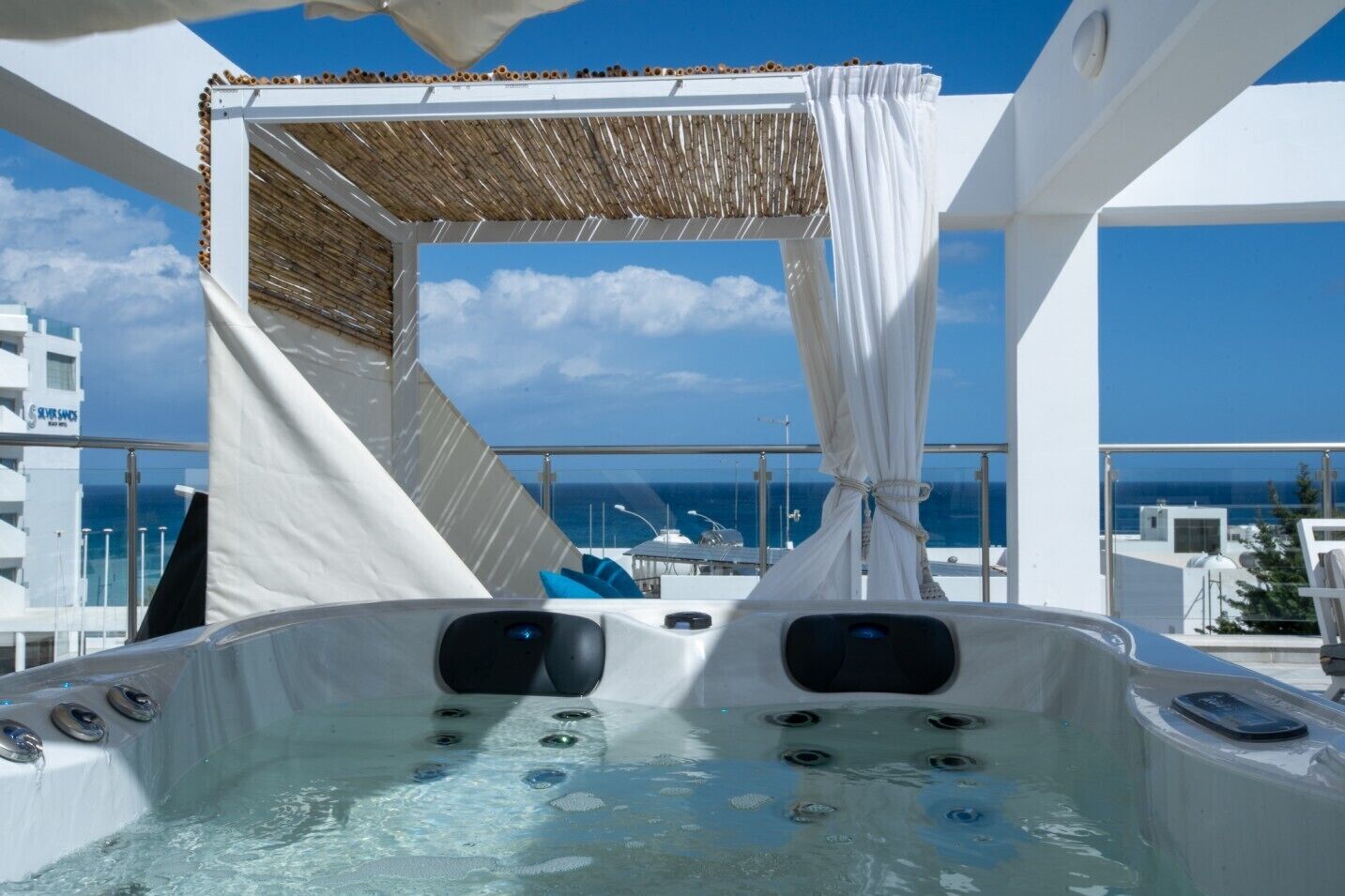 A hot tub with a canopy, overlooking a clear blue sky and the sea.