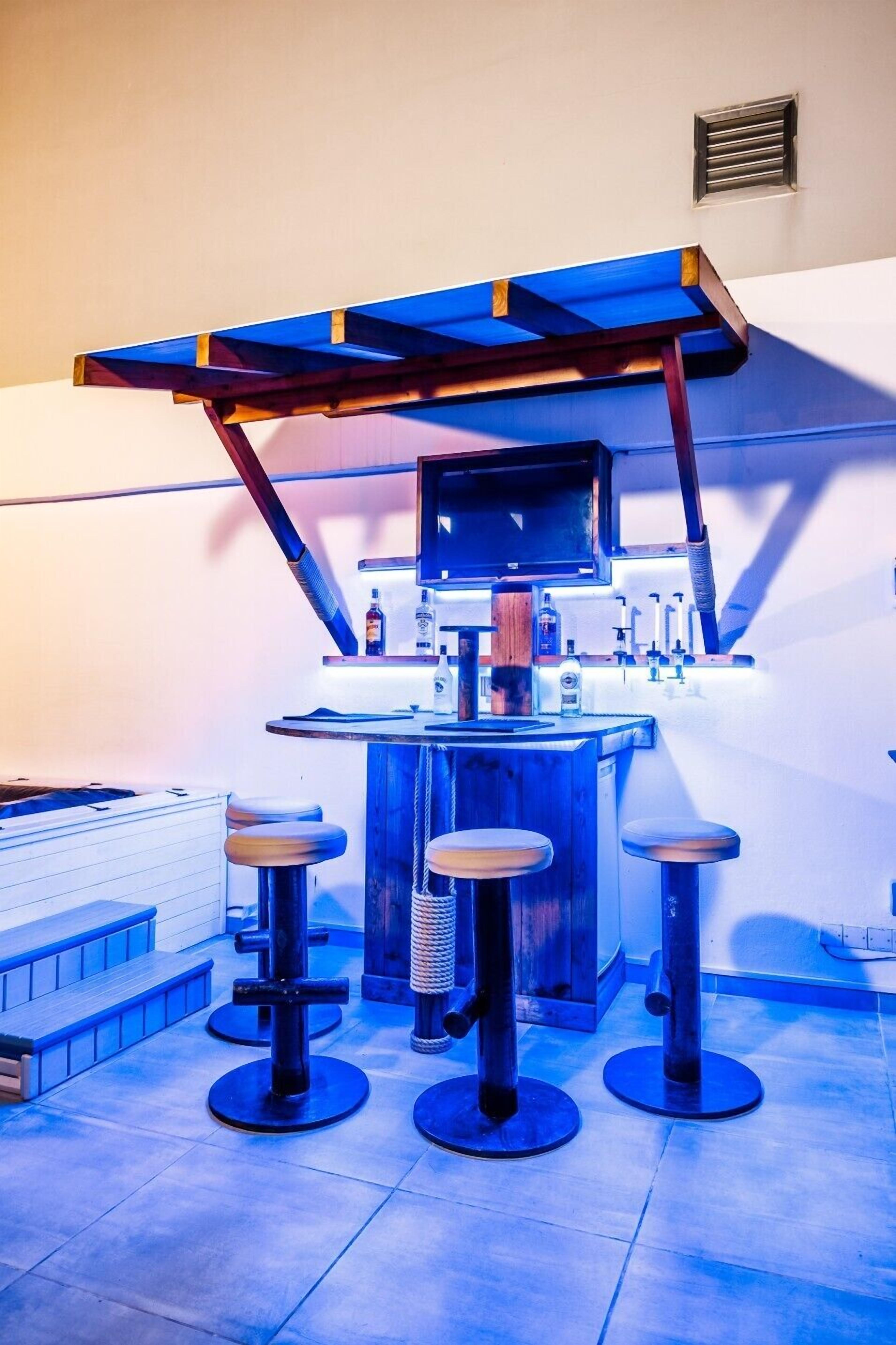 A bar area with stools, a bar counter, and a blue overhead structure.