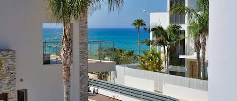 A modern building with a pool, palm trees, and a view of the ocean.