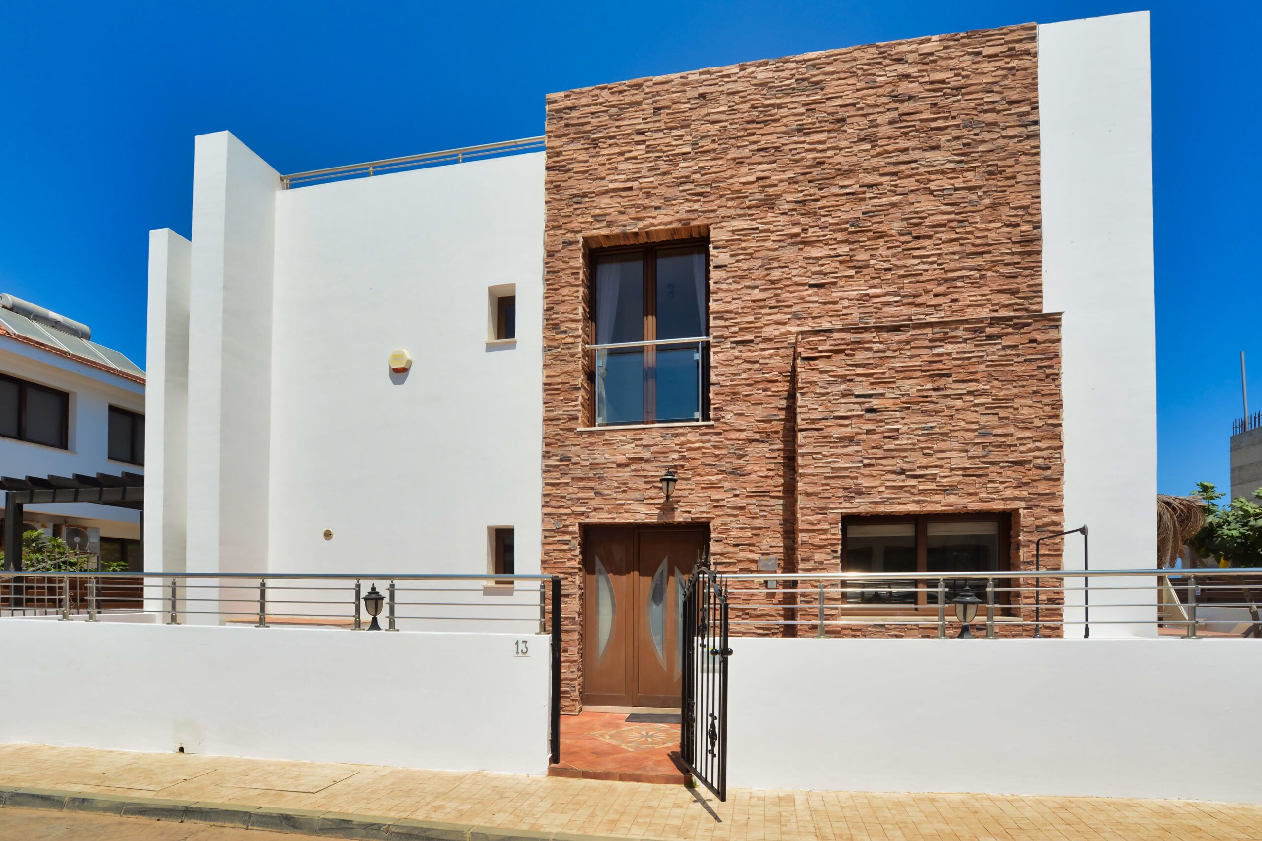 A modern building with a white facade and a stone-textured section.