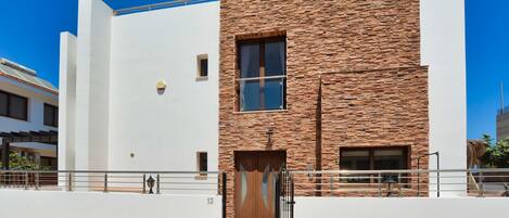 A modern building with a white facade and a stone-textured section.