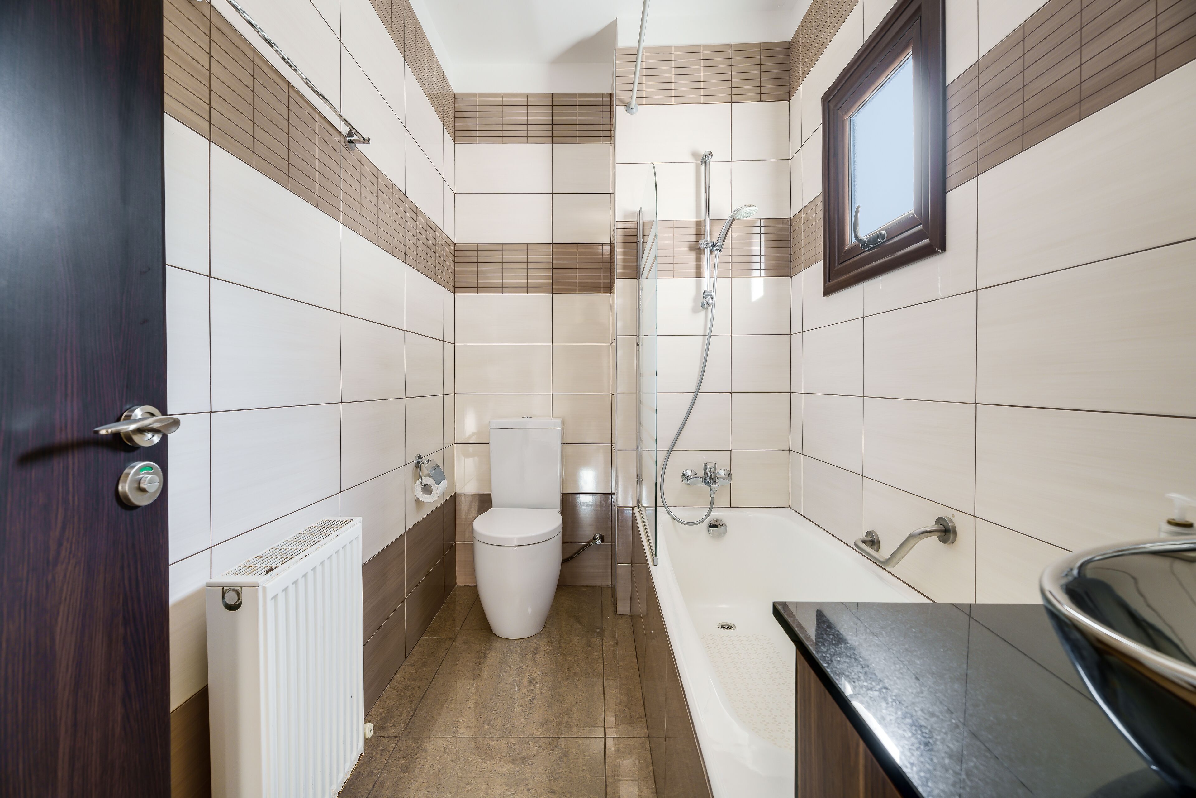 A bathroom with a toilet, shower, and bathtub, tiled walls, and a door.