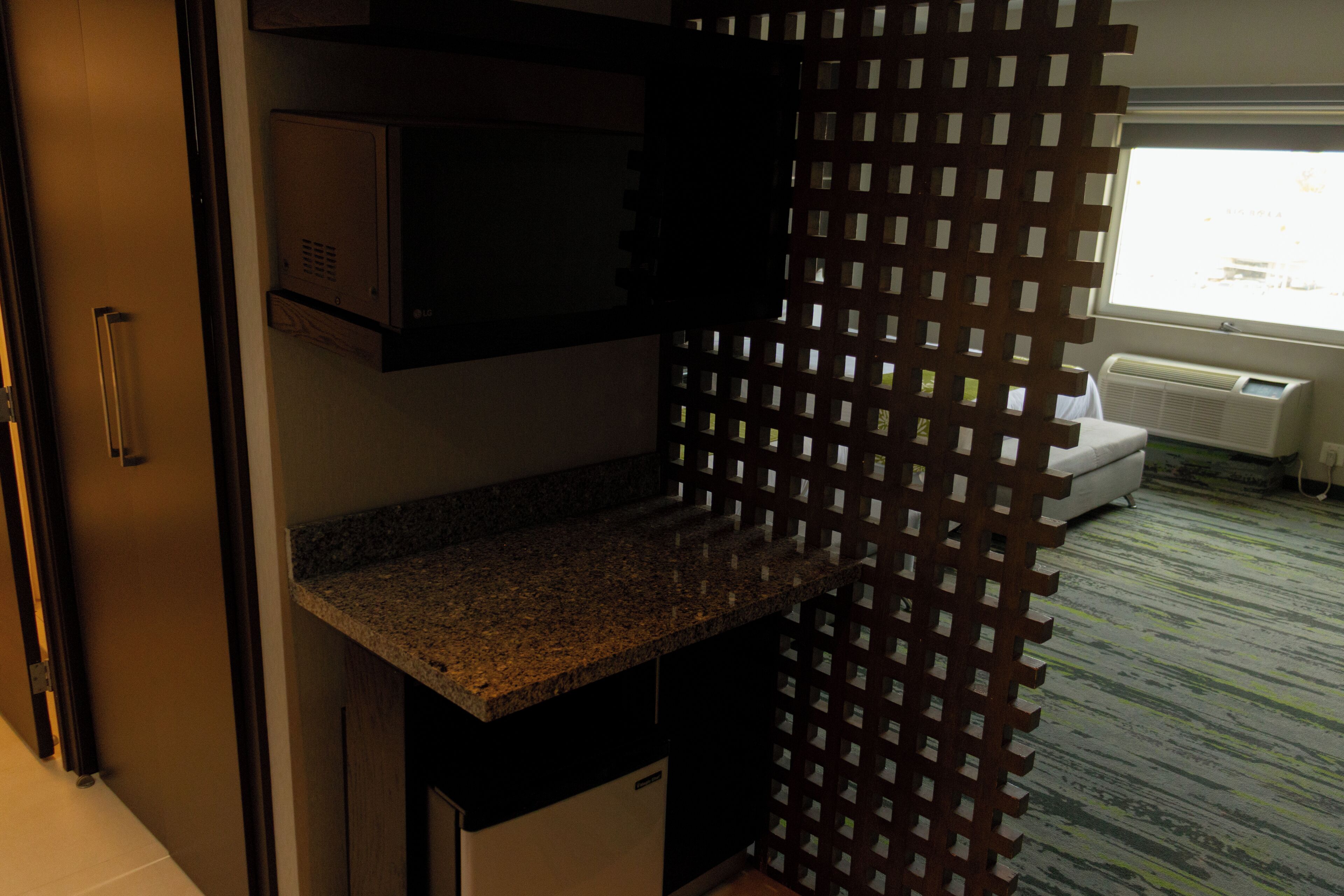 Una cocina con encimera de granito, microondas y refrigerador blanco.