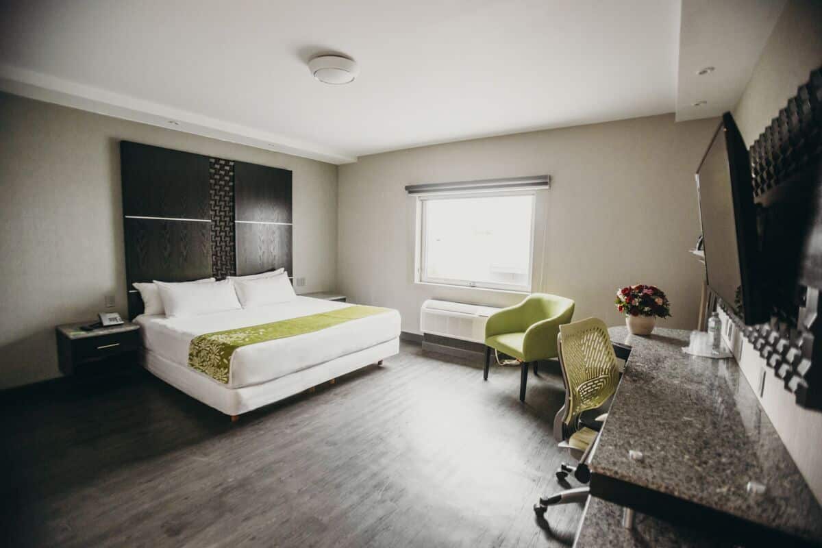 Une chambre d’hôtel équipée d’un lit, d’un bureau, d’une chaise, d’une fenêtre et d’un téléviseur fixé au mur.