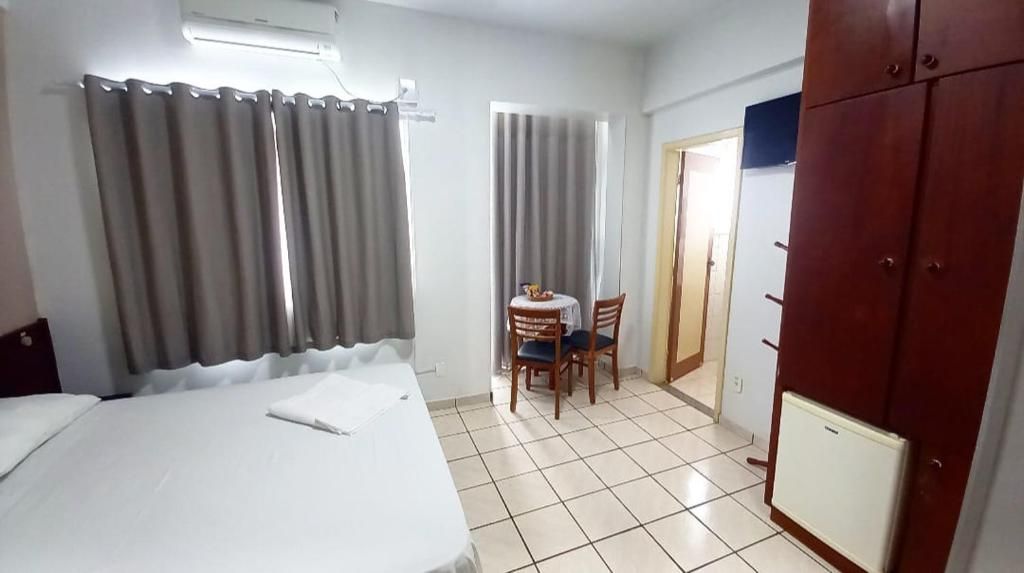 Een hotelkamer met een bed, een tafel met stoelen, een kledingkast en een radiator.
