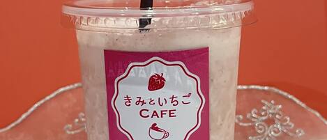 A clear plastic cup with a straw, a pink label, and a logo of a cafe.