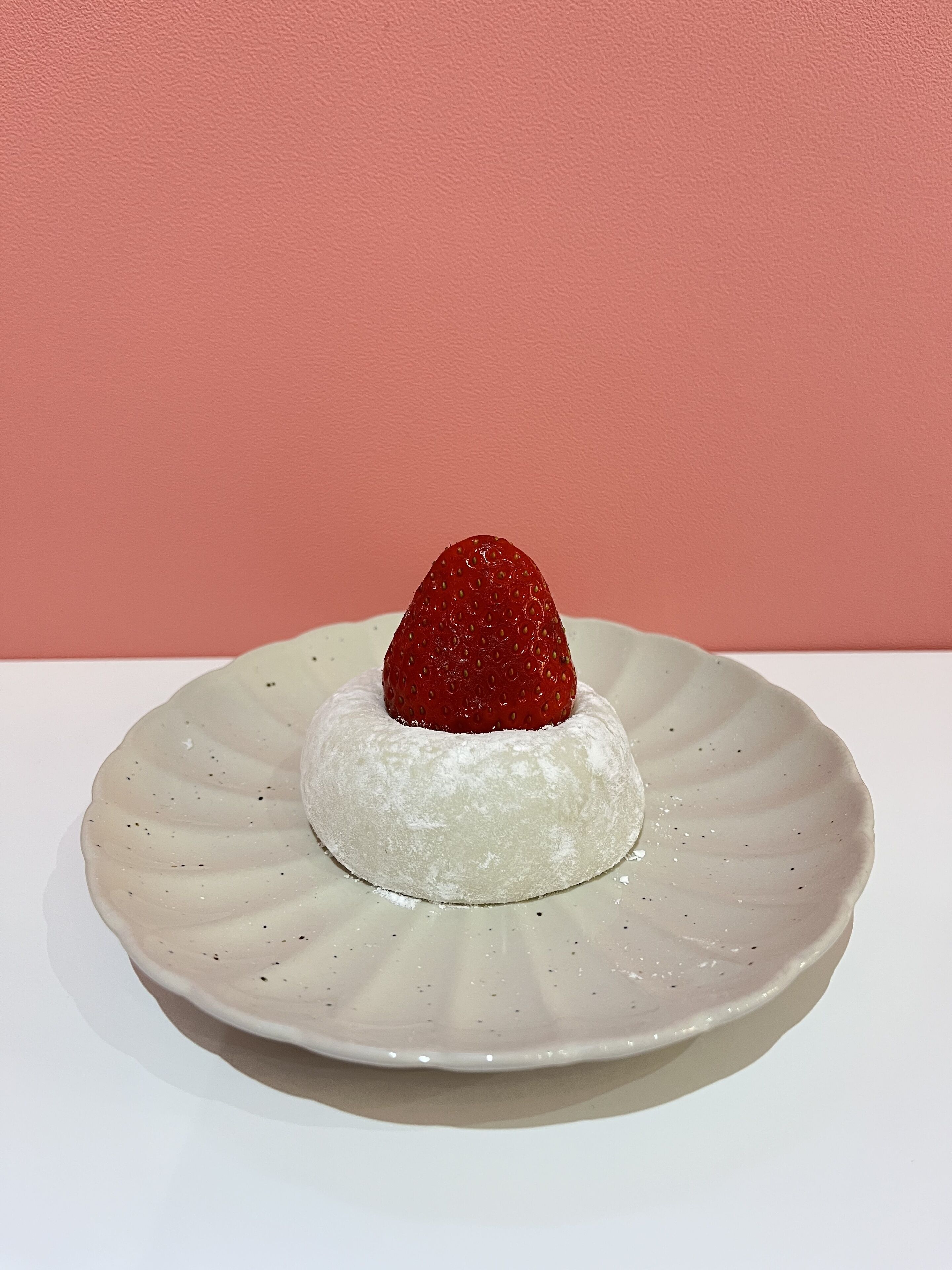 Ein Dessert auf einem Teller vor einem rosa Hintergrund.