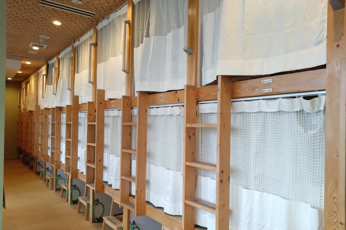 A row of wooden bunk beds with white curtains, each bed separated by a small wooden partition.