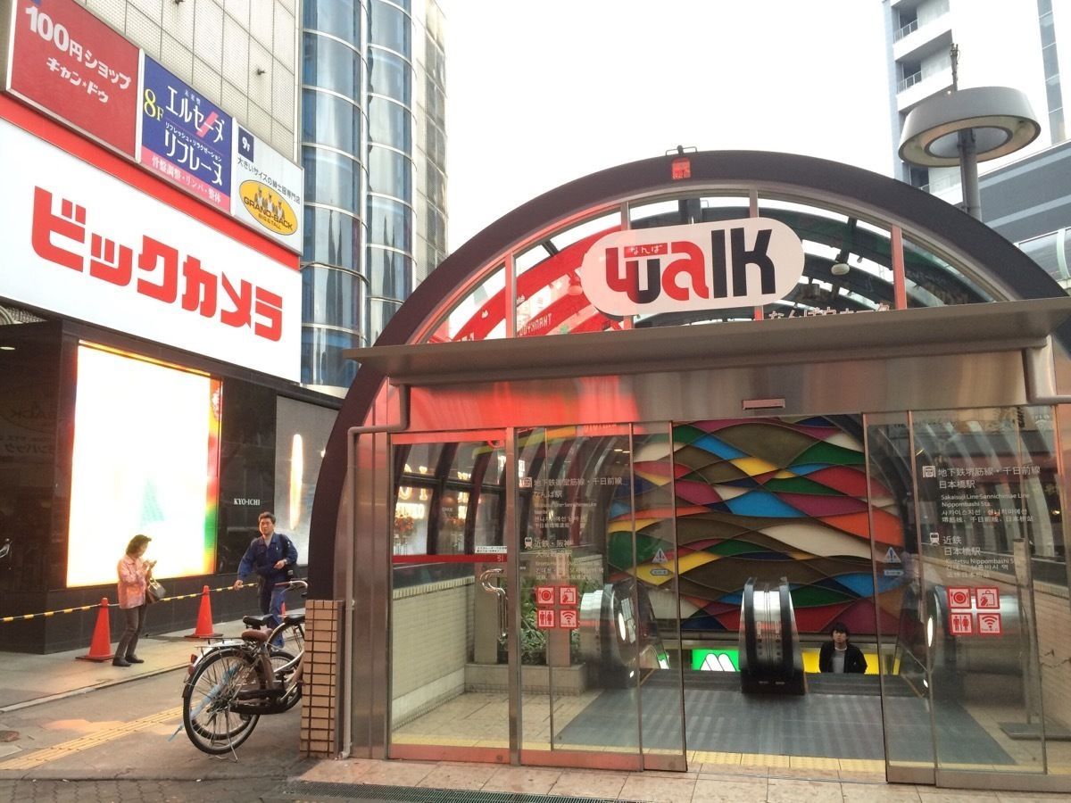 Un pasillo peatonal con un diseño geométrico y llamativo, una entrada de vidrio y un letrero con la palabra 'walk'.