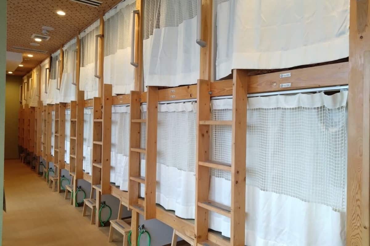 A row of wooden bunk beds with white curtains, each bed having a green ring.