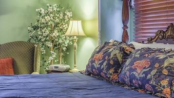 A bedroom with a bed, a nightstand, a lamp, and a decorative plant.