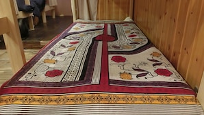 Ein Zimmer mit Holzboden, einem gemusterten Teppich und einem Bett mit Kopfteil.