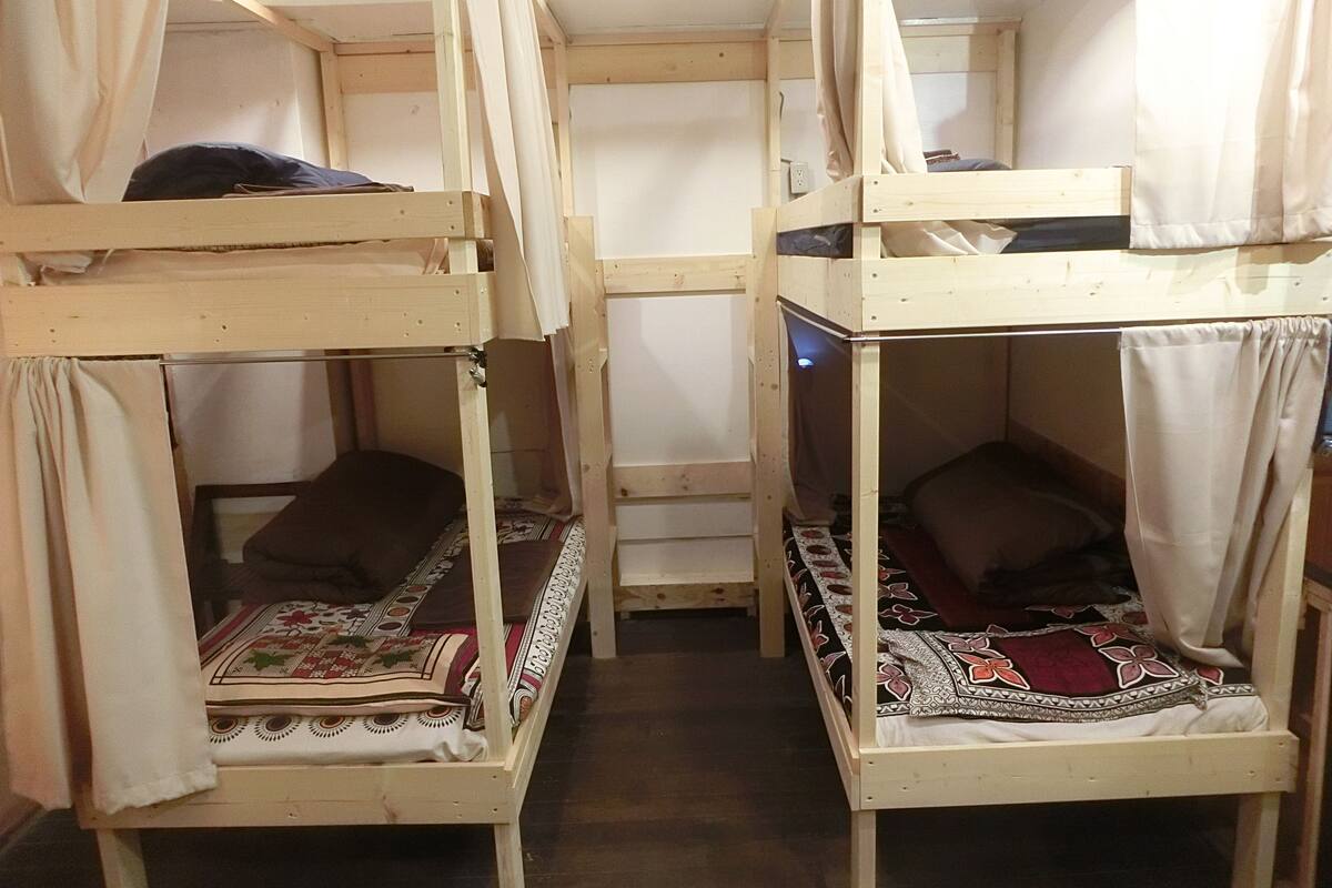 Une chambre avec deux lits superposés, chacun doté d’un ciel de lit et d’une couverture à motifs.