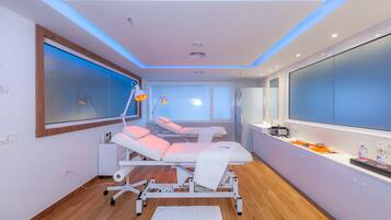 Modern examination room with a white examination table, chair, and sink.