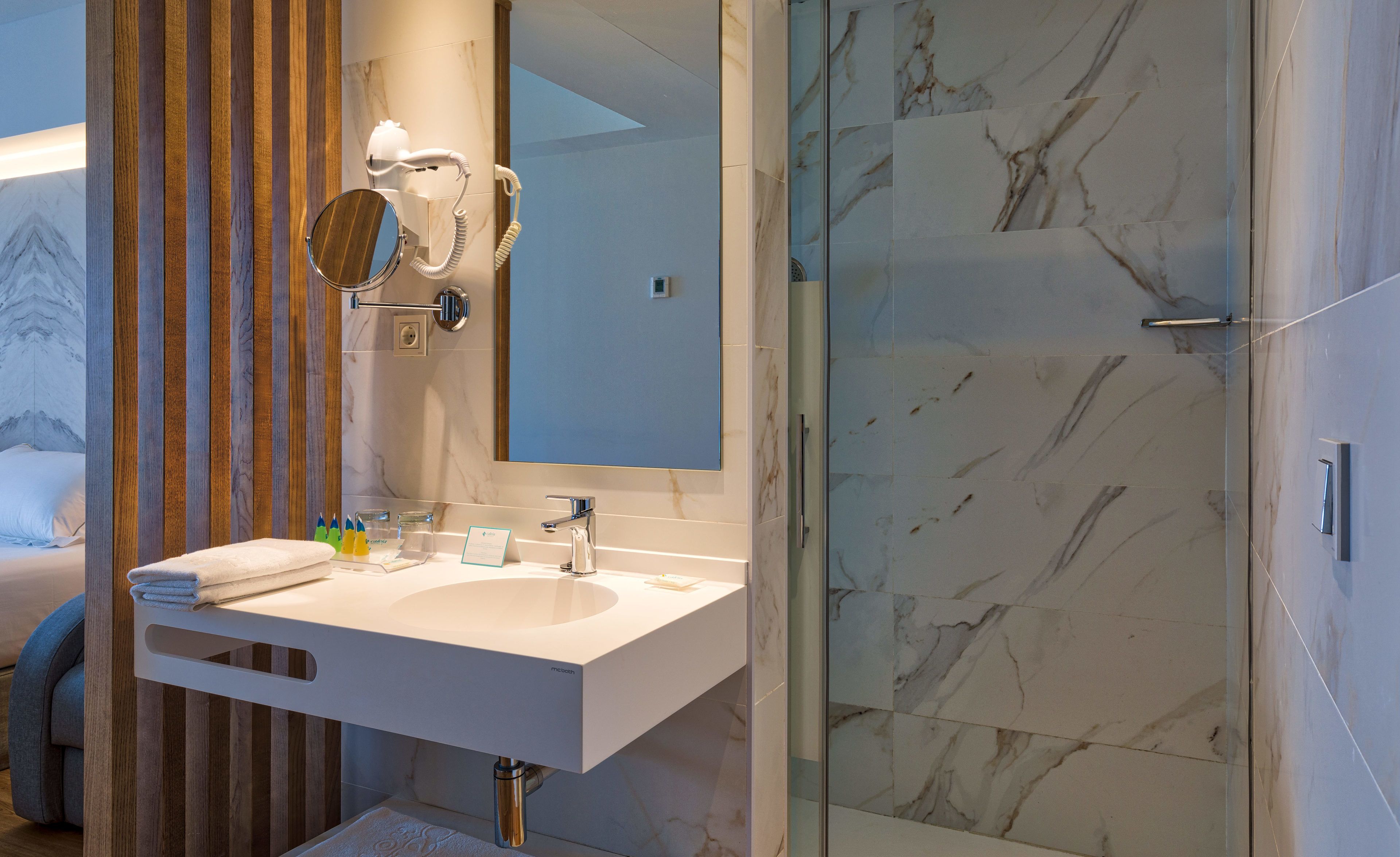 Un baño moderno con un lavamanos blanco, un espejo y un box de ducha de vidrio.