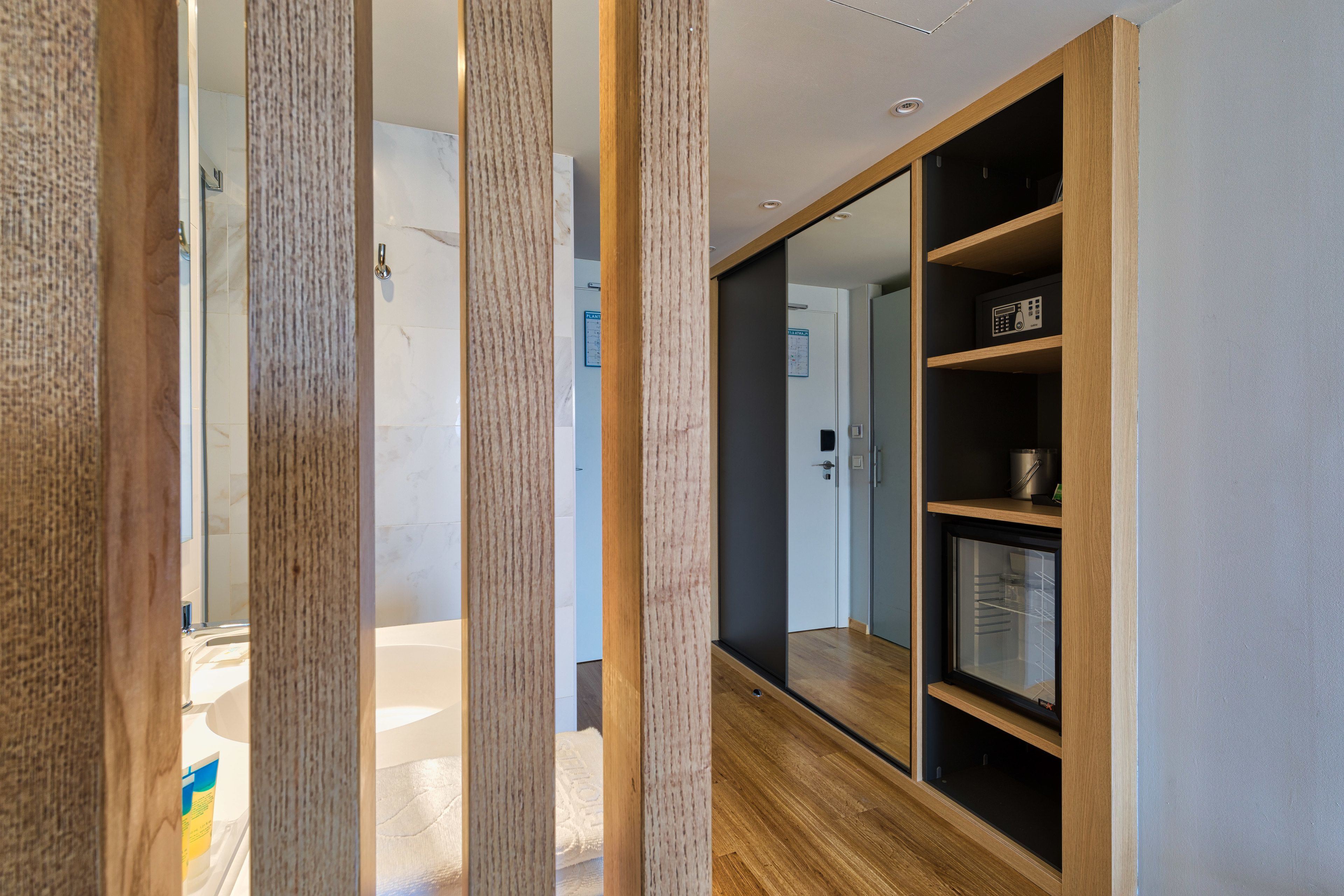 Un intérieur moderne avec des lambris en bois, un grand miroir et des étagères intégrées.